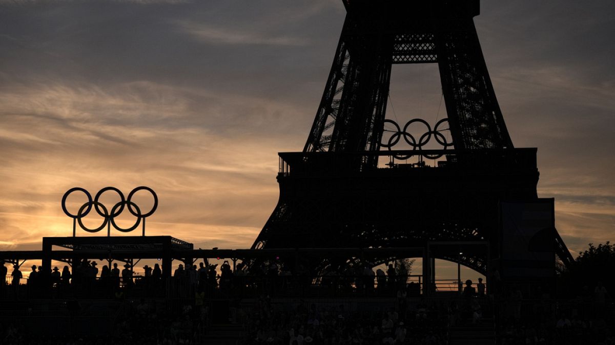 Seyirciler, 6 Ağustos 2024 Salı günü, 2024 Yaz Olimpiyatları'nda Eyfel Kulesi Stadyumu'nda gün batımında Avustralya ve İsviçre arasında oynanan plaj voleybolu çeyrek final maçını izliyor