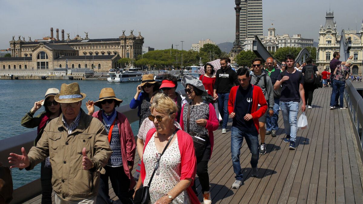 Sur cette photo du mercredi 25 mai 2016, des touristes se promènent sur le port Maremagnum à Barcelone, en Espagne.