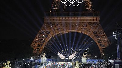 Des volontaires portent les drapeaux des équipes olympiques sur le pont d'Iéna à Paris, France, lors de la cérémonie d'ouverture des JO 2024, le vendredi 26 juillet 2024.