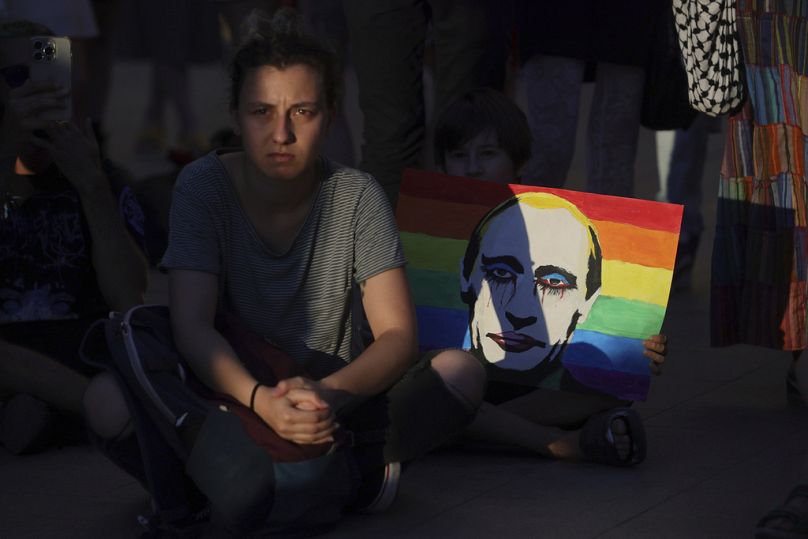 Cartaz com o retrato de Putin numa bandeira arco-íris é visto durante uma manifestação em frente ao parlamento da Bulgária, quinta-feira, 8 de agosto de 2024, em Sófia