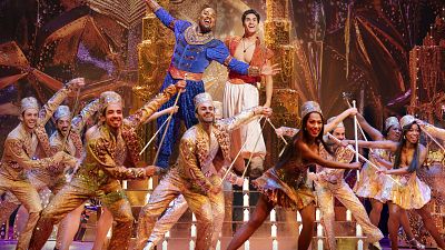 This image released by Disney Theatricals shows Michael James Scott as Genie, and Adi Roy as Aladdin, with the cast during a performance of the musical "Aladdin." 