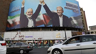 huge banner showing the late Hamas leader Ismail Haniyeh, left, who was killed in an assassination last week, joining hands with Iranian President Masoud Pezeshkian, in a squa