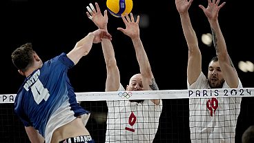 France's Jean Patry (4) hits past Poland's Bartosz Kurek (6) and Norbert Huber (99) during a gold medal men's volleyball match at the 2024 Summer Olympics