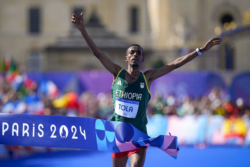 Ethiopia's Tamirat Tola celebrates after crossing the finish line to win the gold medal at the end of the men's marathon competition at the 2024 Olympics