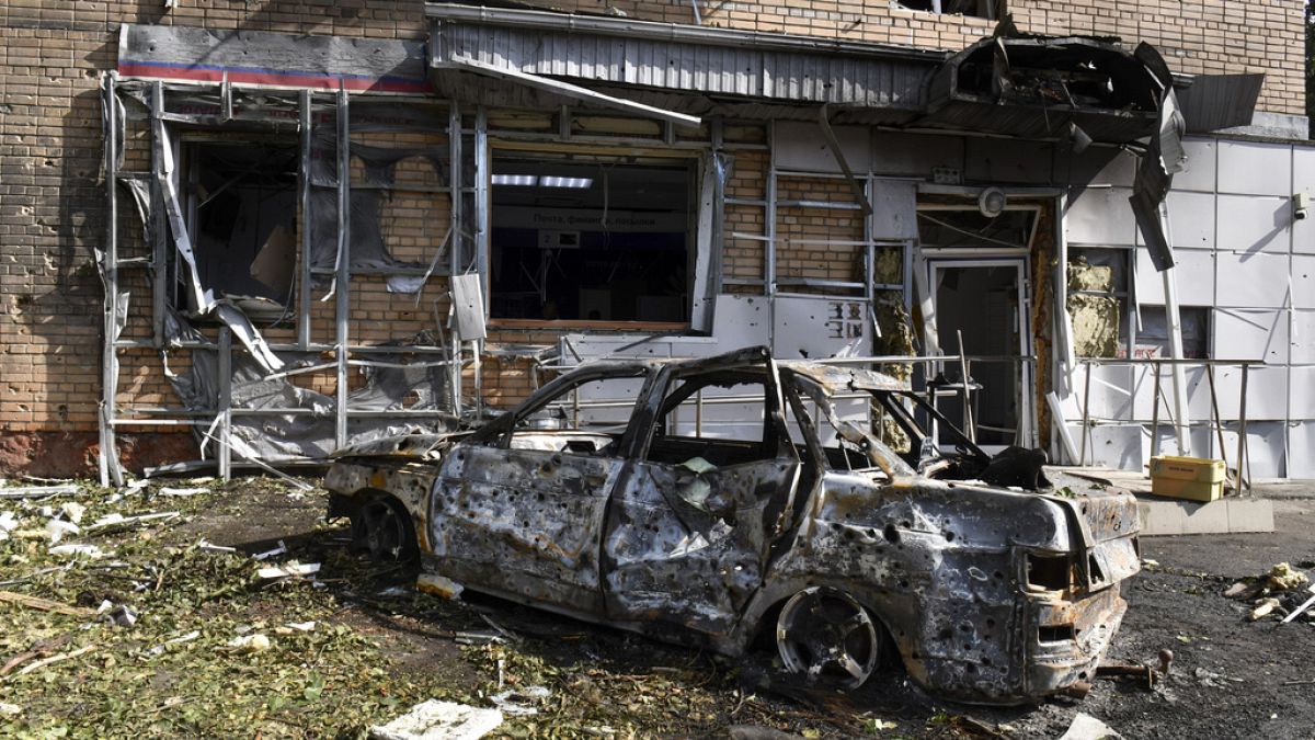 Un'auto bruciata davanti a un edificio danneggiato dai bombardamenti ucraini a Kursk, in Russia, 11 agosto 2024