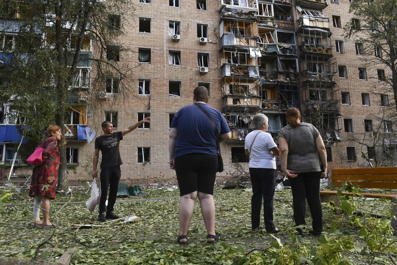 Residents of an apartment building damaged after shelling by the Ukrainian side stand near the building in Kursk, Russia, Sunday, Aug. 11, 2024.