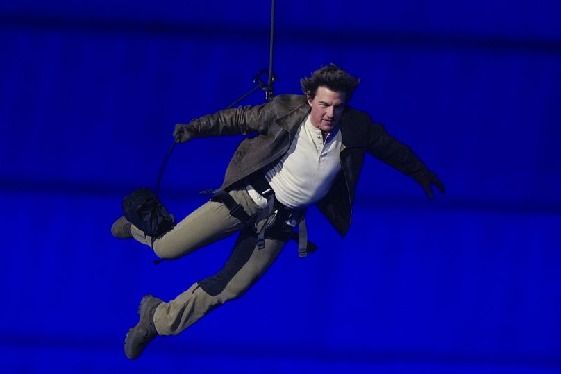 Tom Cruise viene calato sullo Stade de France durante la cerimonia di chiusura delle Olimpiadi estive del 2024, domenica 11 agosto 2024, a Saint-Denis, in Francia