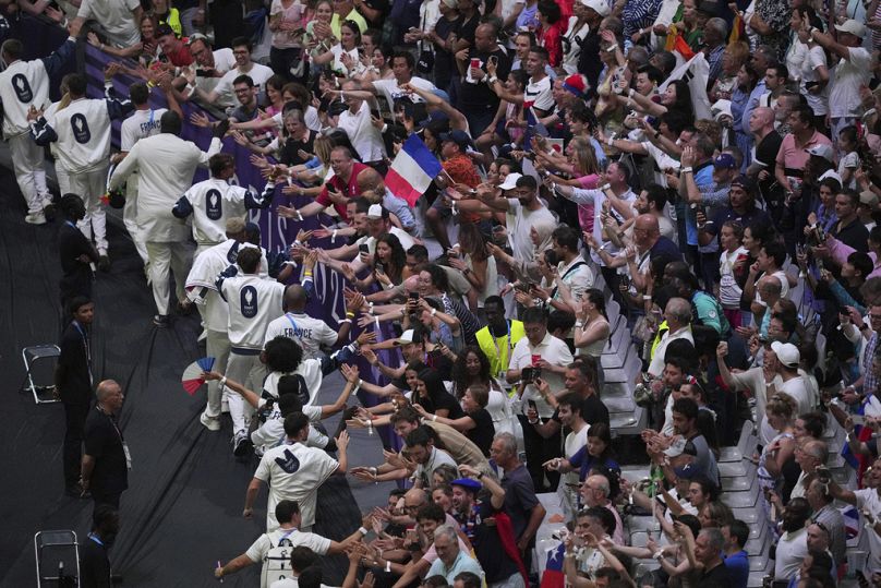 Espectadores aplaudem os atletas franceses durante a cerimónia de encerramento dos Jogos Olímpicos de verão de 2024 no Stade de France, domingo, 11 de agosto de 2024