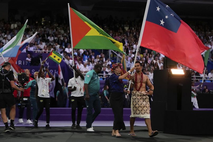 Gli atleti sventolano le bandiere durante la cerimonia di chiusura delle Olimpiadi estive del 2024 allo Stade de France, domenica 11 agosto 2024, a Saint-Denis, Francia