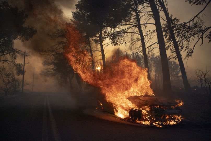 A car burns in Varnava village during a wildfire in Athens, Greece, Sunday, August 11, 2024. 