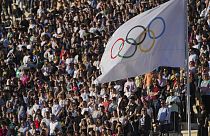 Olimpiyat bayrağı, 26 Nisan 2024 Cuma günü Atina'da, 1896 yılında ilk modern oyunların düzenlendiği Panathenaic stadyumunda Olimpiyat ateşinin devir teslim töreni sırasında dalgalanıyor