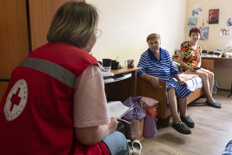 Un'operatrice della Croce Rossa russa con alcune donne evacuate in un centro di accoglienza temporanea a Kursk, Russia, 11 agosto 2024