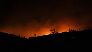 Smoke, lighted by fire, rises near Varnava village during a wildfire, north of Athens, Greece, Sunday, Aug. 11, 2024.