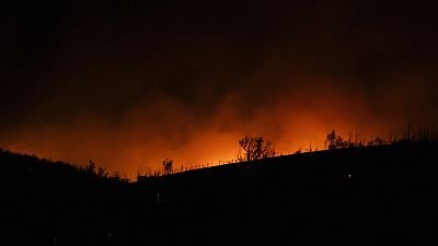 Smoke, lighted by fire, rises near Varnava village during a wildfire, north of Athens, Greece, Sunday, Aug. 11, 2024.