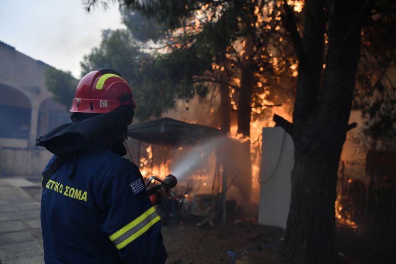 A firefighter works to extinguish the flames at a burning house in northern Athens, Monday, Aug. 12, 2024.