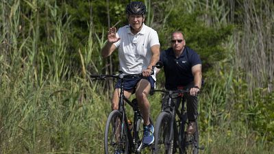 President Joe Biden, followed by a Secret Service agent, rides his bike at Gordons Pond in Rehoboth Beach, Delaware.