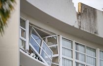 A broken window hands precariously at the Double Tree by Hilton Hotel in Cairns, Australia, after a helicopter crashed into its roof early Monday, Aug. 12, 2024.