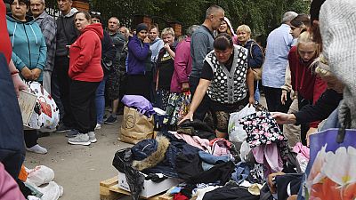 Pessoas fazem fila para receber ajuda humanitária num centro de distribuição em Kursk, Rússia, segunda-feira, 12 de agosto de 2024. 