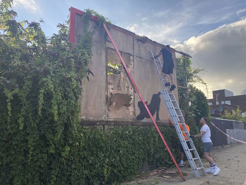 Contractors dismantle a billboard with the new Banksy artwork depicting a stretching cat in Cricklewood, north-west London, Saturday, 10 August 2024.