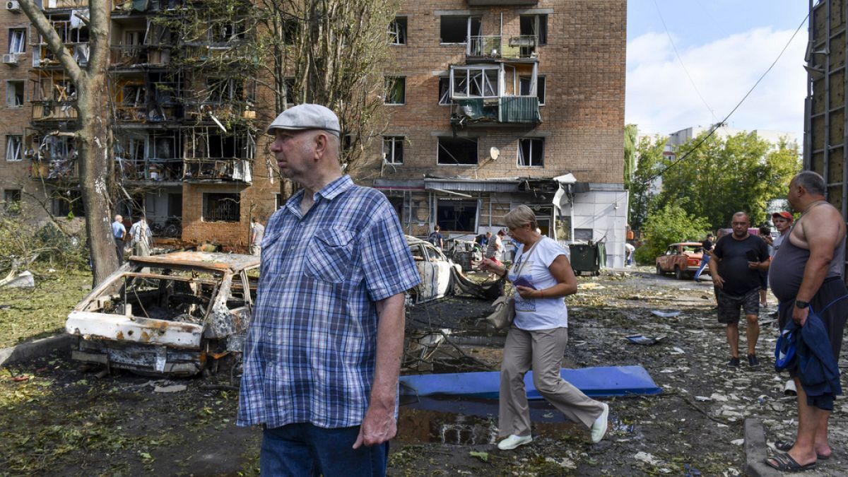 Rusya'nın Kursk kentinde, 11 Ağustos 2024, Pazar günü, Ukrayna tarafından yapılan bombardıman sonrasında hasar gören bir apartmanın yakınında yürüyen insanlar