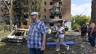 People walk near an apartment building damaged after shelling by the Ukrainian side, in Kursk, Russia, Sunday, Aug. 11, 2024