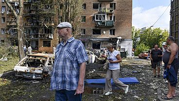 People walk near an apartment building damaged after shelling by the Ukrainian side, in Kursk, Russia, Sunday, Aug. 11, 2024