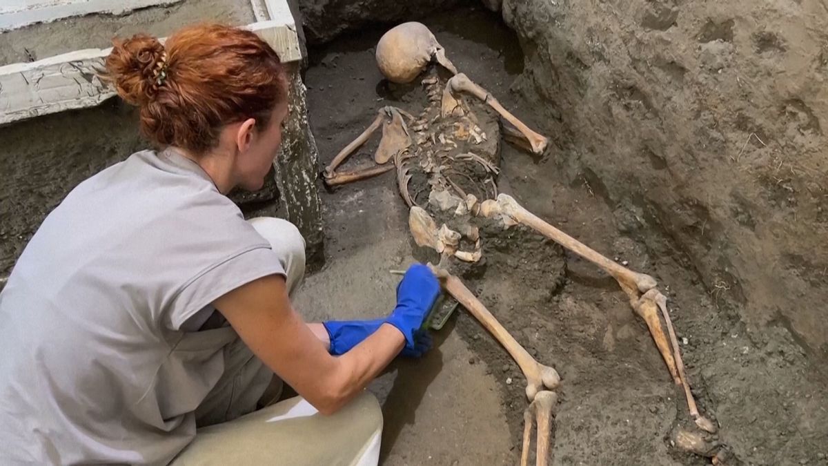 Ein Archäologe reinigt die Überreste des Skeletts eines Mannes, der in Pompeji während des Ausbruchs von 79 n. Chr. ums Leben kam