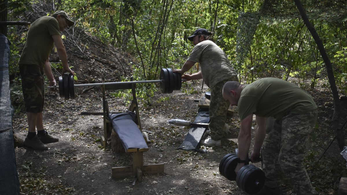 Soldiers of Ukraine's 65th Separate Mechanised Brigade drill with barbell and dumbbells on the frontline in Zaporizhzhia region, Ukraine, Wednesday, July 31, 2024. 