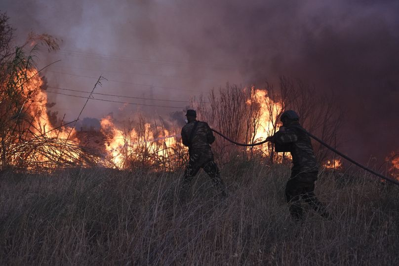 Vigili del fuoco al lavoro per spegnere un vasto incendio vicino ad Atene, Grecia