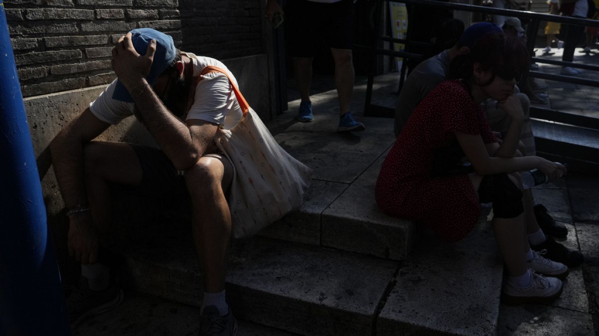 Imagen de varias personas resguardadas a la sombra en una calle, un día de temperaturas asfixiantes en Italia.