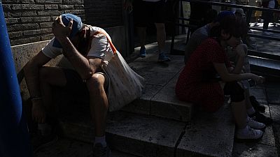 Imagen de varias personas resguardadas a la sombra en una calle, un día de temperaturas asfixiantes en Italia.