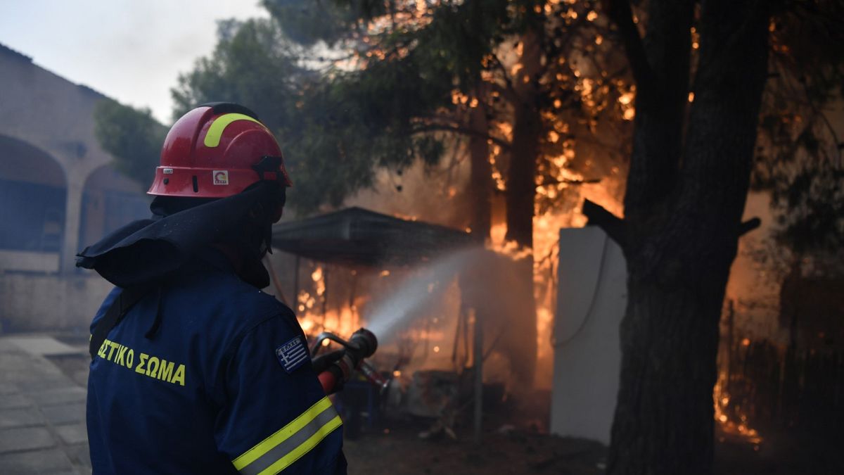 Un bombero trabaja para extinguir las llamas en una casa en llamas en el norte de Atenas, el lunes 12 de agosto de 2024.