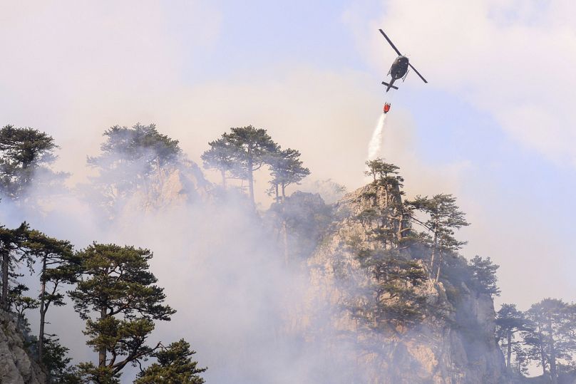 A helicopter drops water over a fire in Tjentiste, Bosnia, Tuesday, Aug. 13, 2024. Five helicopters are extinguishing a fire at Sutjeska National Park.