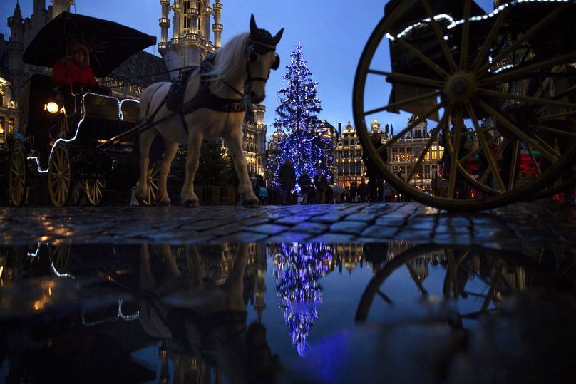 FILE - Horse-drawn carriages ride past a Christmas tree in the Grand Square of downtown Brussels, Thursday, Dec. 20, 2018.