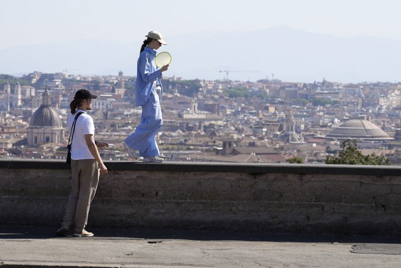 A woman walks on the balcony overlooking the city skyline on the Pincio hill in Rome. 