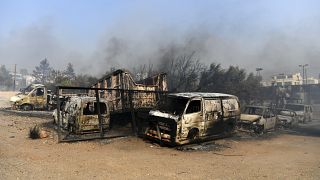 Flames burn a vehicle at a business during a fire in northern Athens, Monday, Aug. 12, 2024,