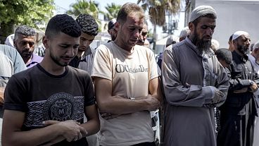 Mohammad Abu Al-Qumsan, Center, prays next to the bodies of his 4-day-old twin children, killed in the Israeli bombardment of the Gaza Strip, Tuesday, Aug. 13, 2024.