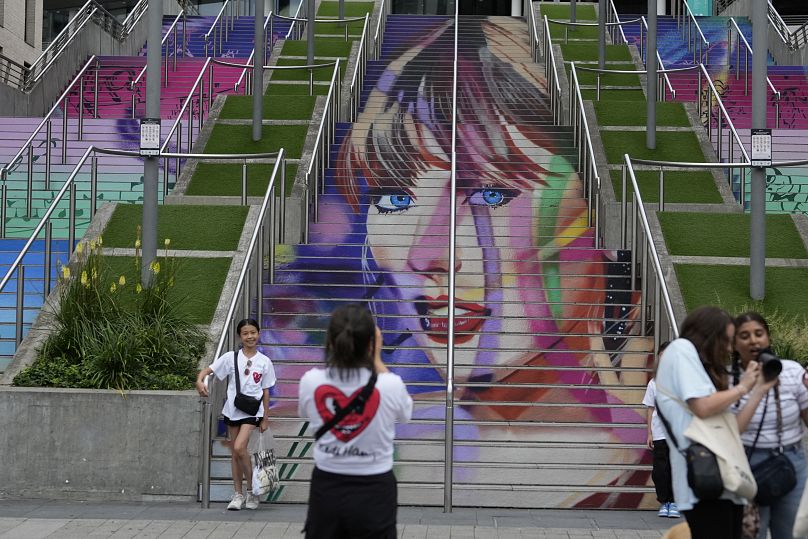 Fans pose by a Taylor Swift portrait painted on a stairway at Wembley Stadium in London - Wednesday 14 August