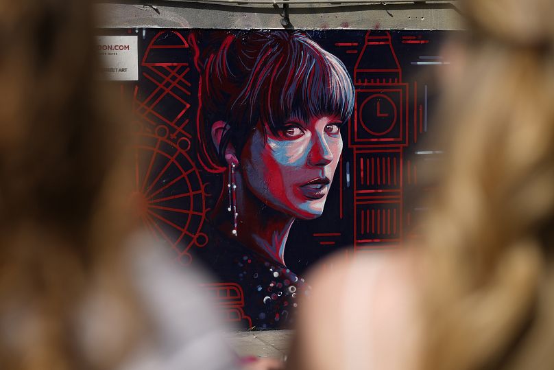 La gente observa un nuevo mural con el retrato de Taylor Swift diseñado por Kate Clayton, que se inauguró en Shoreditch, en el este de Londres, el martes 13 de agosto.