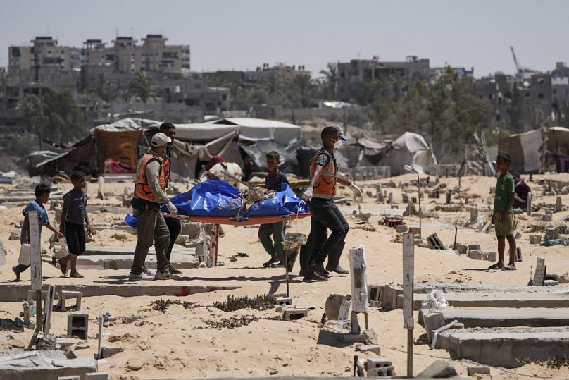 Workers carry a body, one of more than 80 bodies returned by Israel, to a cemetery in Khan Younis, 5 August 2024