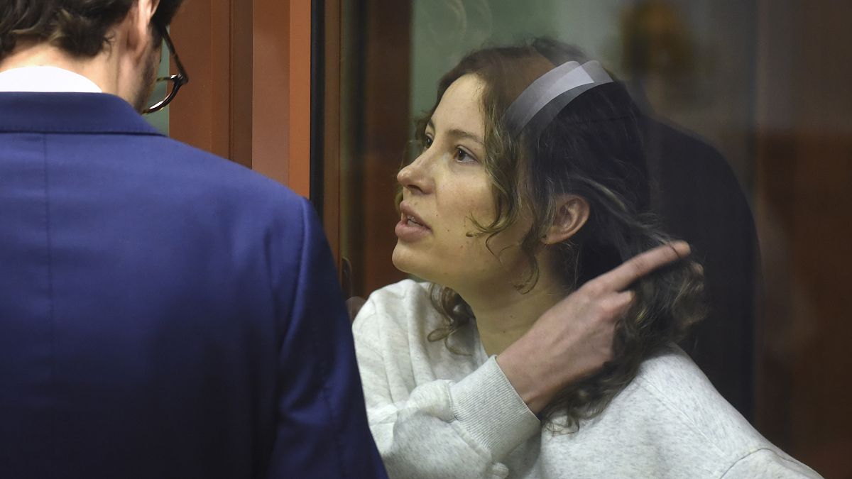 Ksenia Karelina sits in a glass cage in a court room in Yekaterinburg, Russia.