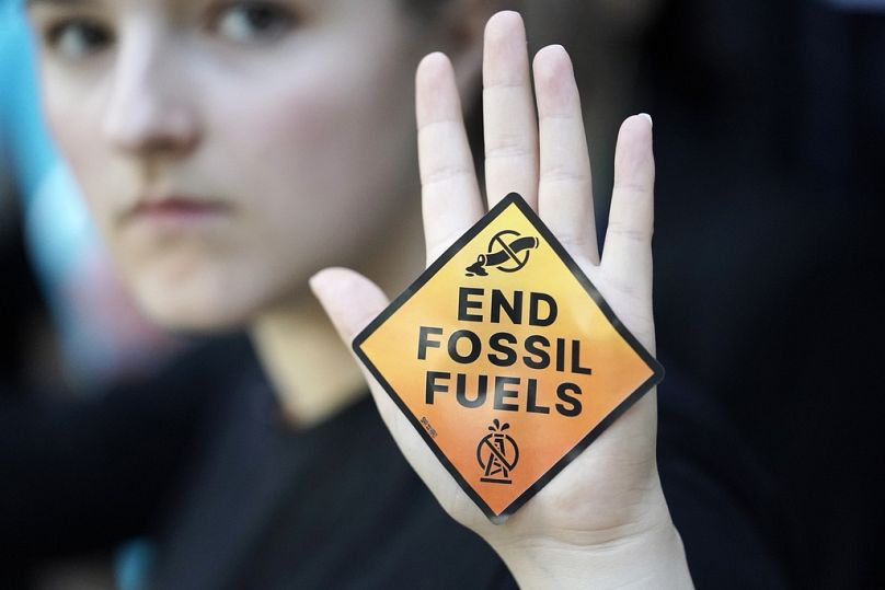 A demonstrator displays a sign reading "end fossil fuels" at the COP28 Climate Summit in Dubai in 2023