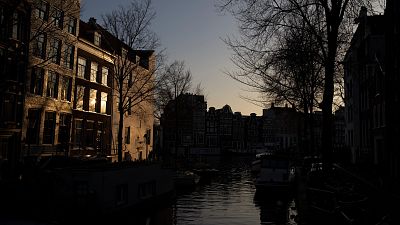 The setting sun bounces off a building in the Amsterdam city center skyline, Netherlands, Monday, Feb. 13, 2023. 