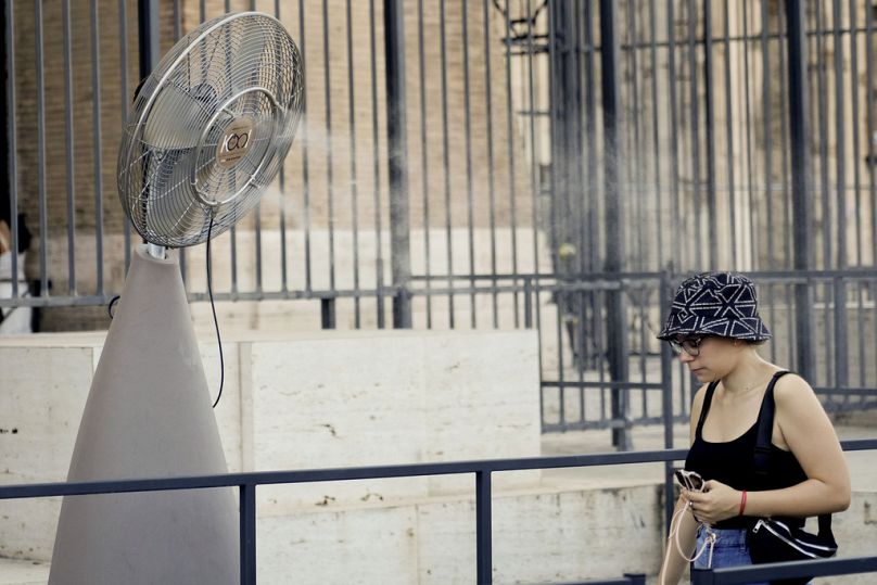 Una donna entra nel Colosseo passando davanti a un ventilatore a Roma, 10 agosto 2024