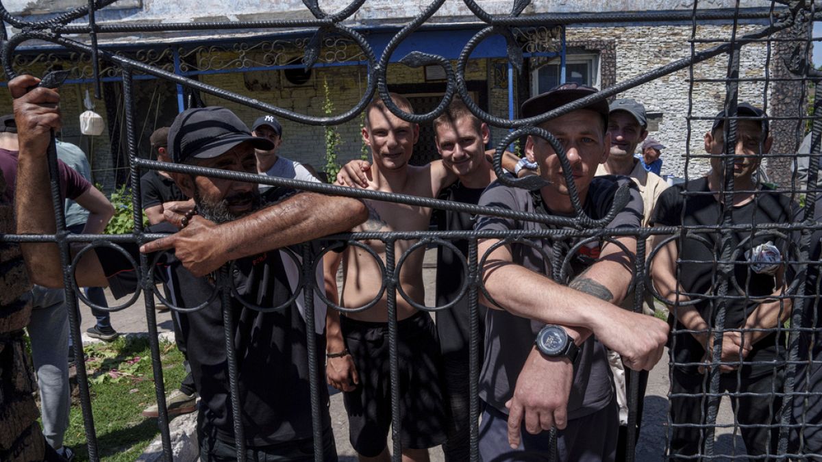 Des prisonniers se tiennent derrière la clôture de la cour de la caserne d'une prison, dans la région de Dnipro, en Ukraine, le vendredi 21 juin 2024. 