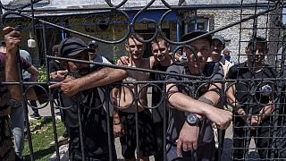 Des prisonniers se tiennent derrière la clôture de la cour de la caserne d'une prison, dans la région de Dnipro, en Ukraine, le vendredi 21 juin 2024. 