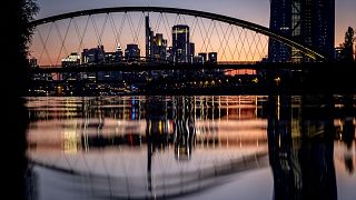 The European Central Bank and the banking district are reflected in the river Main after sunset in Frankfurt