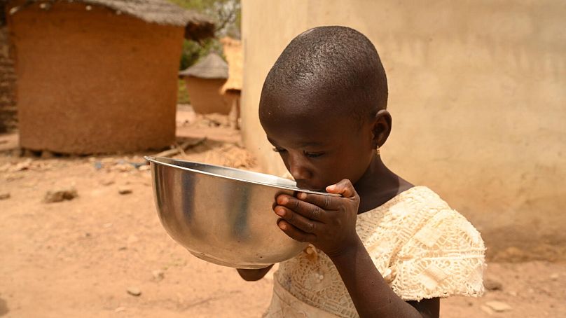 Una bambina beve dell'acqua nel villaggio di Nambekha, nel nord della Costa d'Avorio 