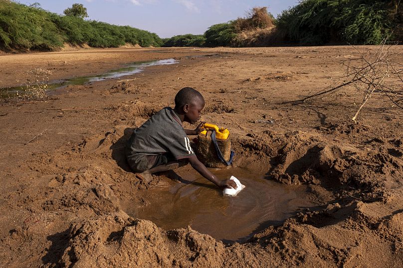 Un bambino raccoglie la poca acqua che rimane in un fiume prosciugato a causa della grave siccità in Somalia 