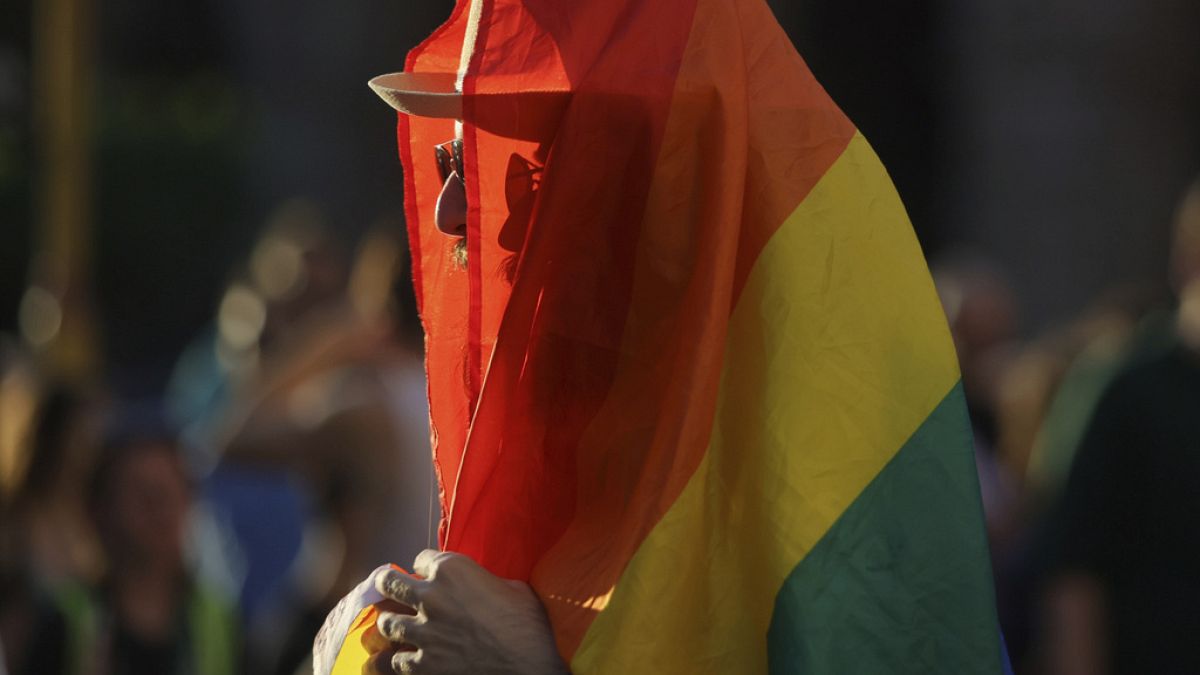 Ein Mensch eingewickelt in eine LGBT-Flagge.